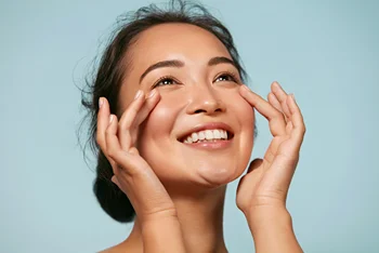 a woman with radiant skin touches her face